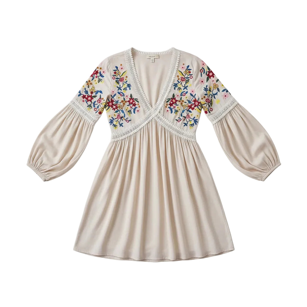 Woman wearing a white dress with floral embroidery holding a wooden bag against a gray background