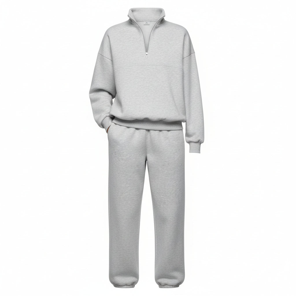 Person wearing a gray tracksuit holding a coffee cup against a neutral background