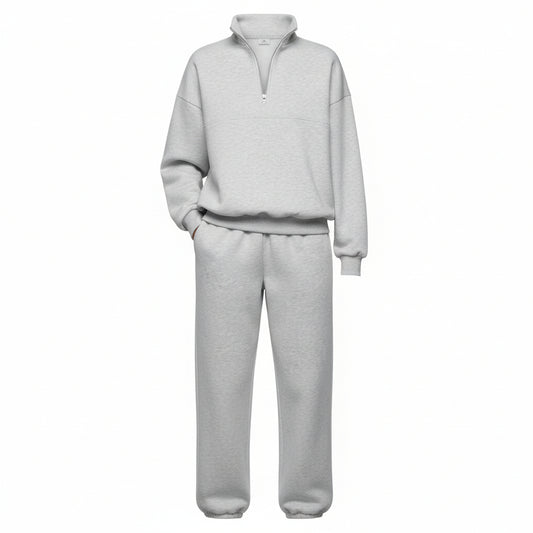 Person wearing a gray tracksuit holding a coffee cup against a neutral background
