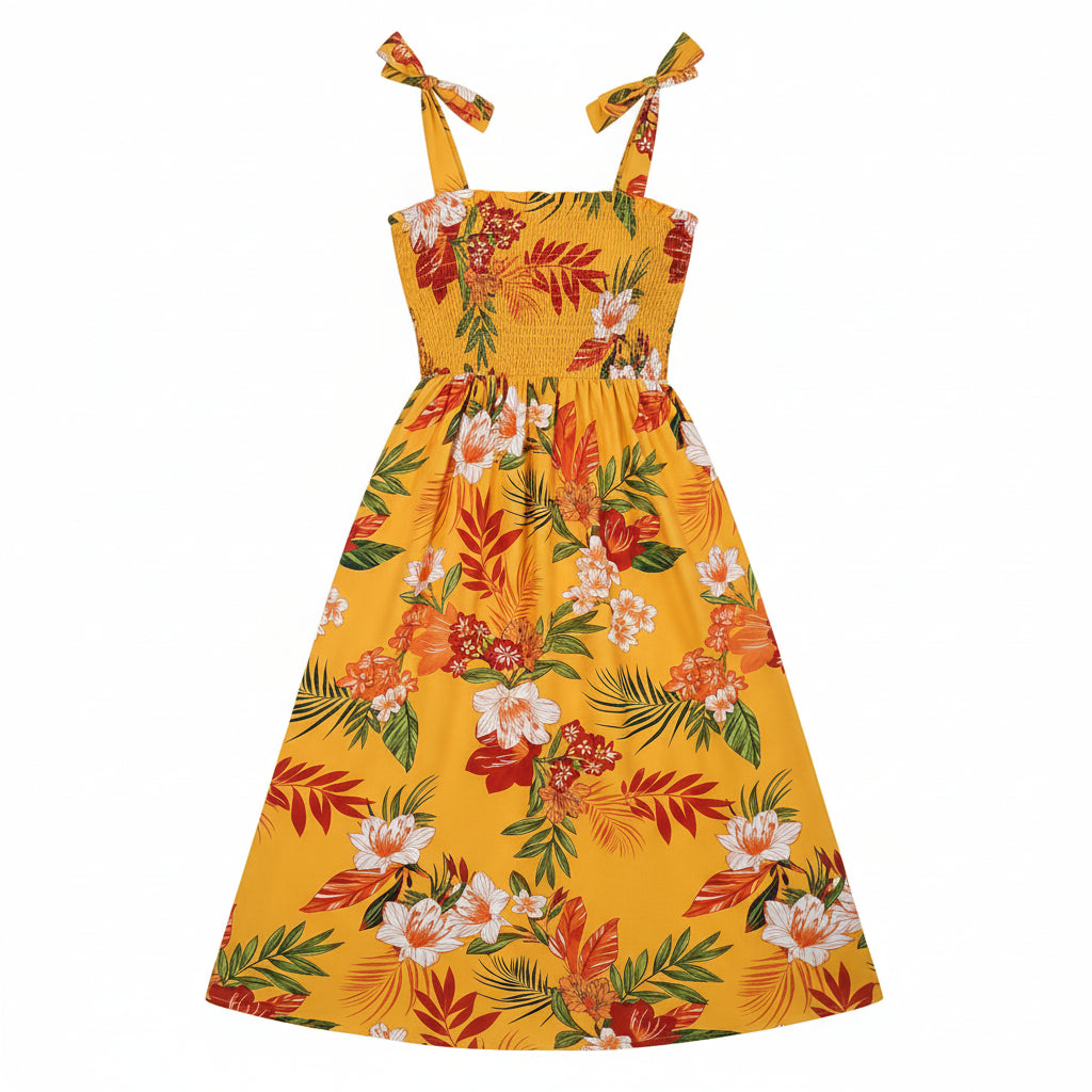Woman wearing a yellow floral dress in a bright room with a plant and chair.