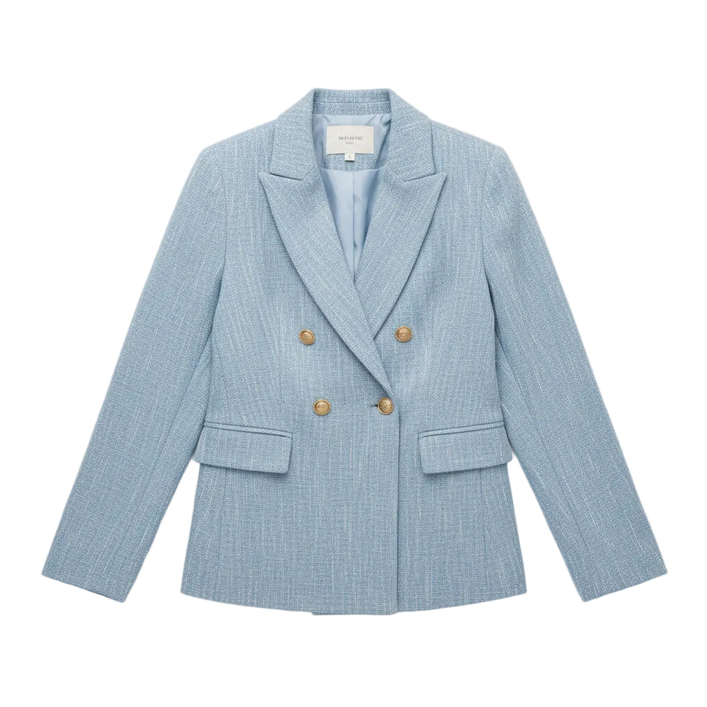 Woman wearing a light blue blazer with gold buttons, holding a white handbag.
