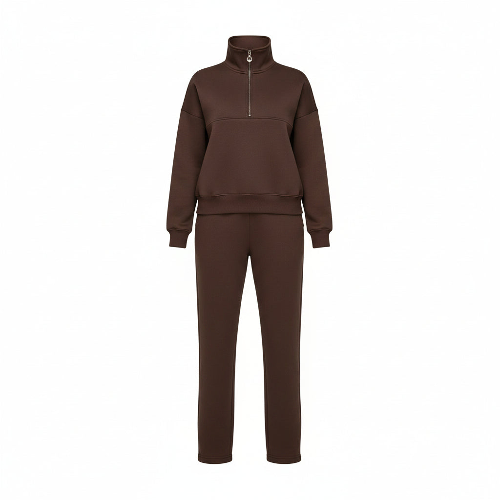 Person wearing a brown tracksuit in a room with a gray wall and white sofa.