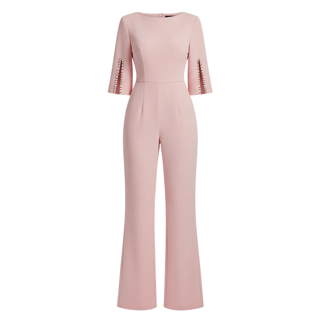Woman wearing a pink jumpsuit with pearl embellishments against a plain background