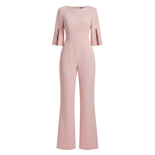 Woman wearing a pink jumpsuit with pearl embellishments against a plain background