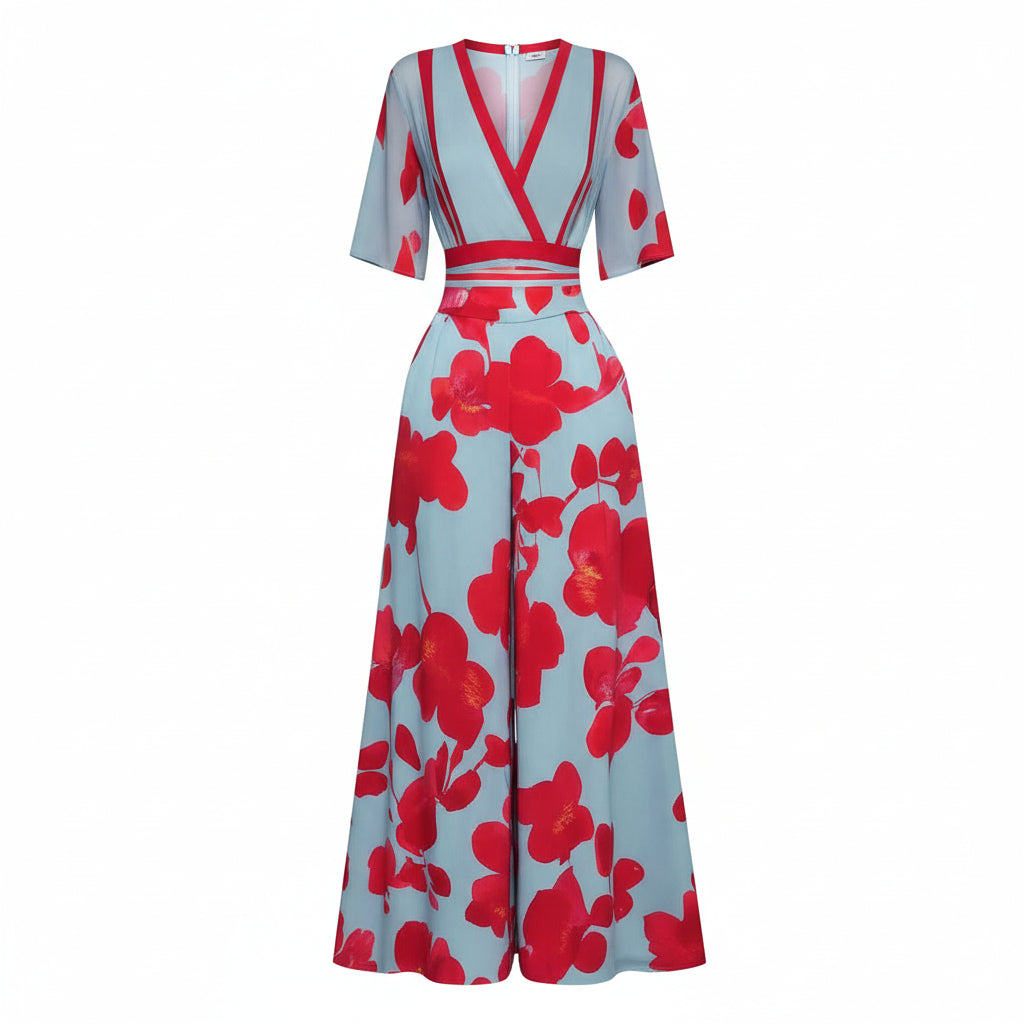 A model on a runway wearing a light blue maxi dress with bold red floral prints and red trim details.
