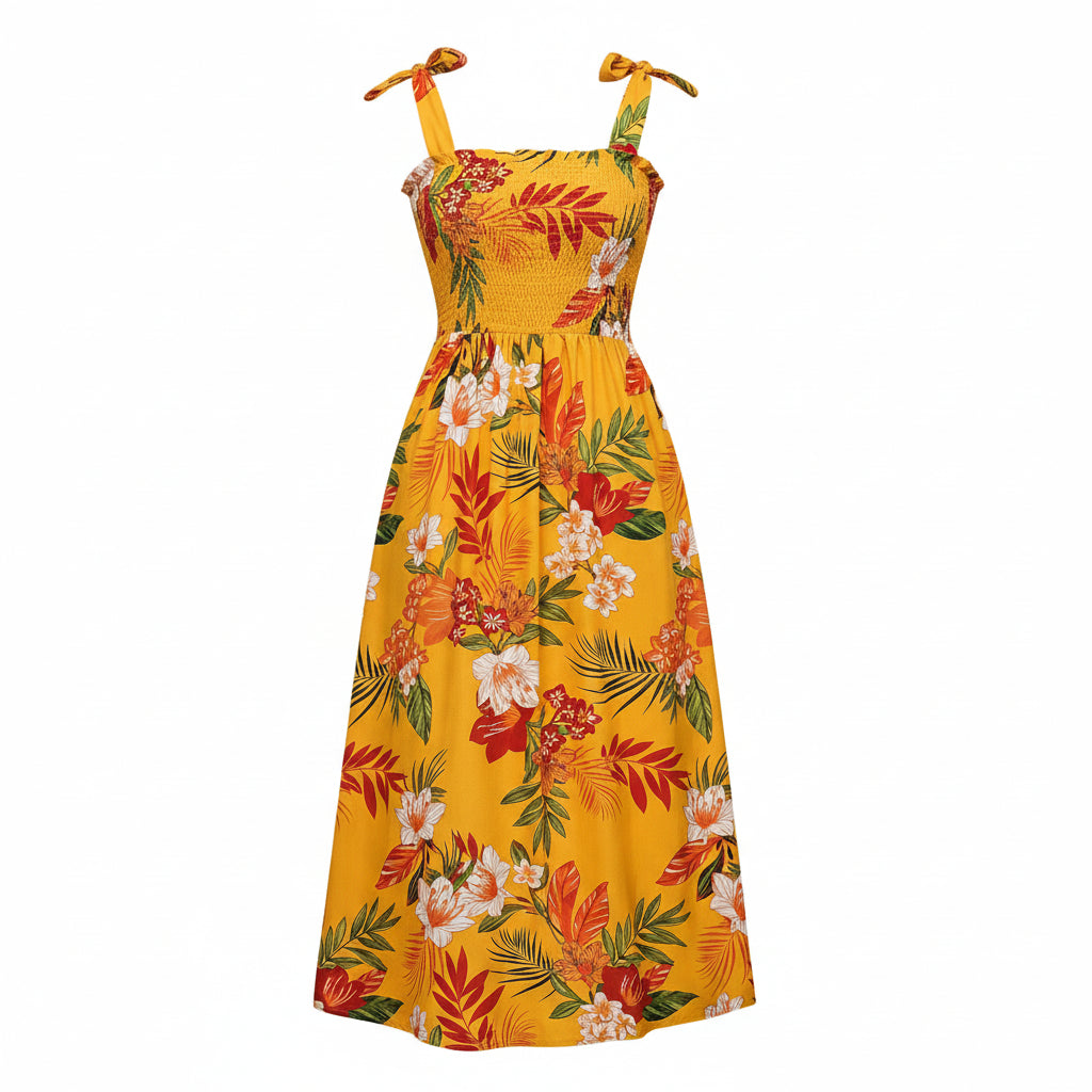Woman wearing a yellow floral dress in a bright room with a plant and chair.