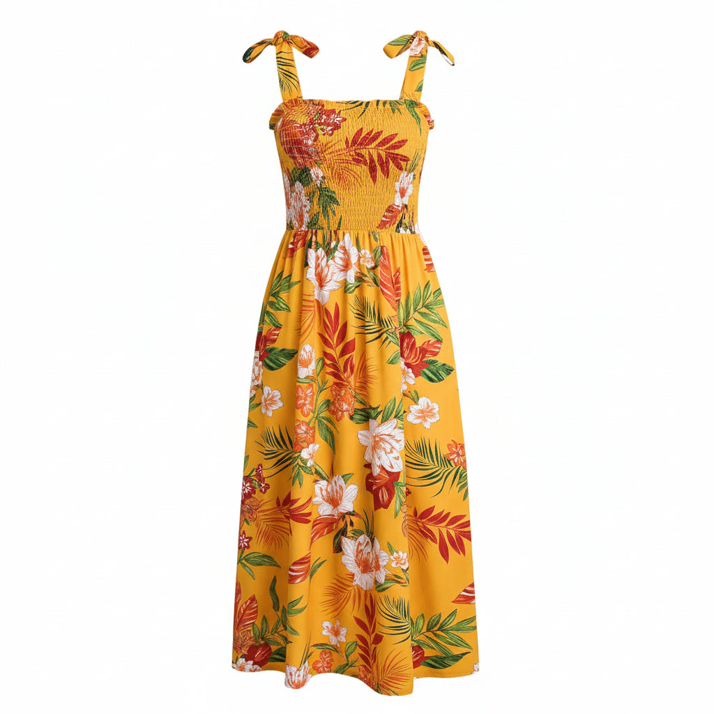 Woman wearing a yellow floral dress sitting on a couch with a plant in the background