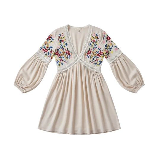 Woman wearing a white dress with floral embroidery holding a wooden bag against a gray background