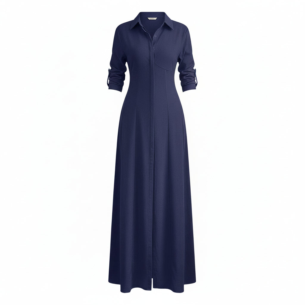 Woman wearing a long navy dress with a slit in a room with white walls and wooden flooring.